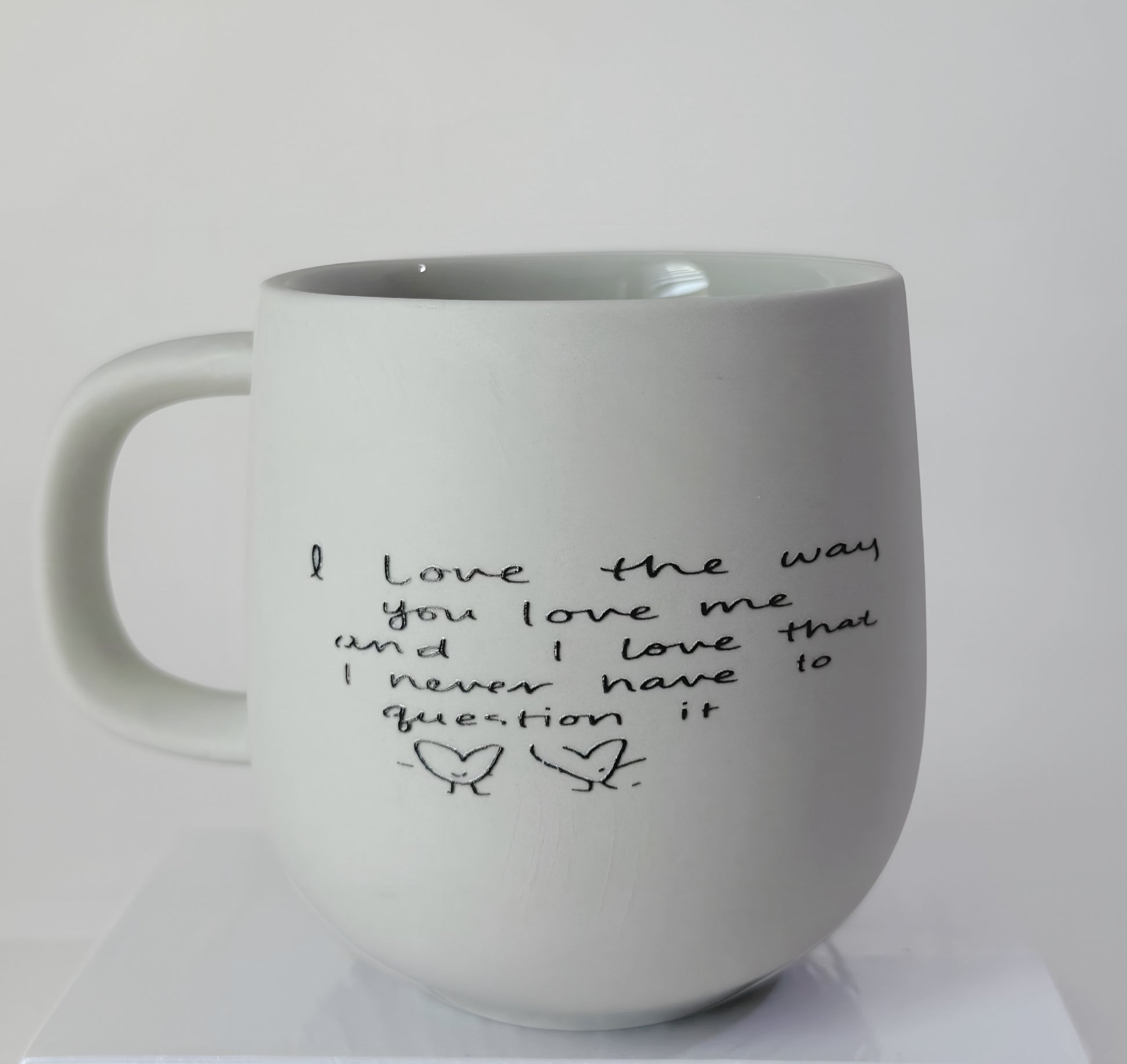 White mug with handwritten text on a white background