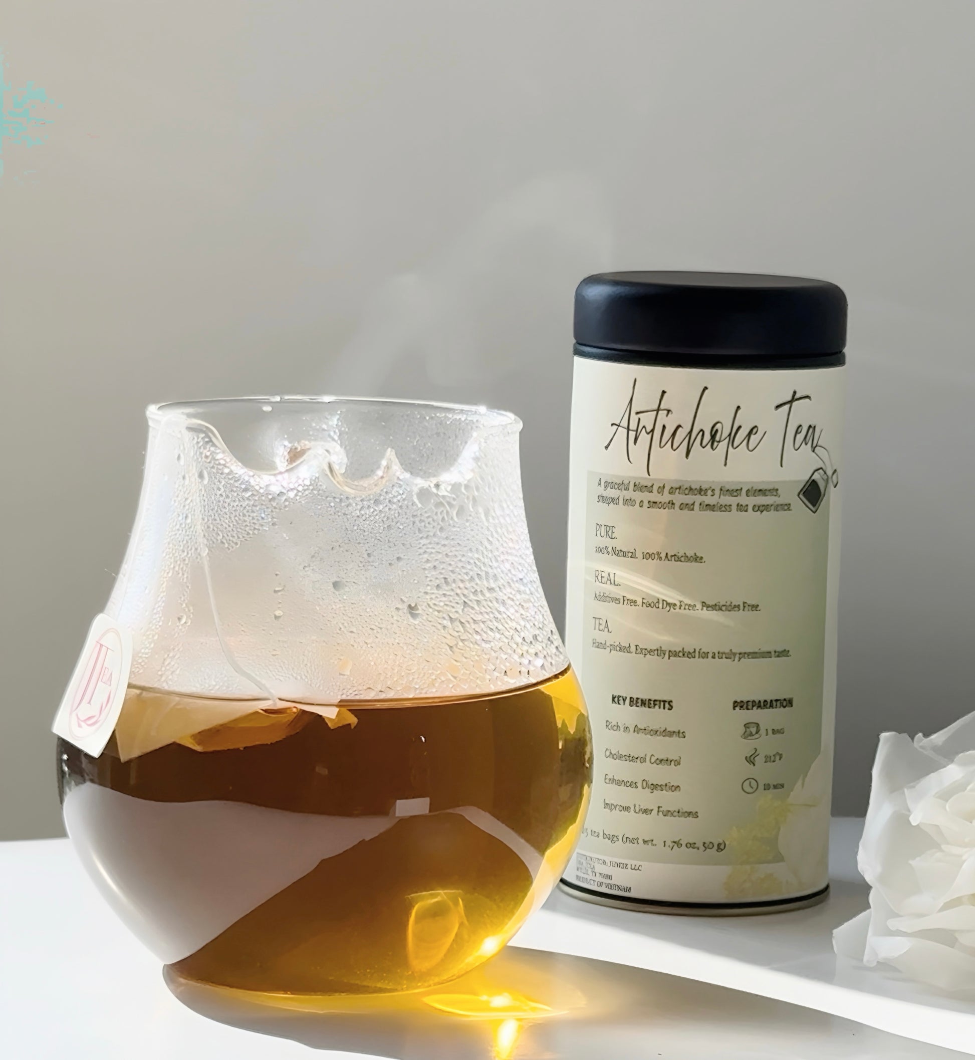 Glass of iced tea with a canister labeled 'Artichoke Tea' on a light surface.