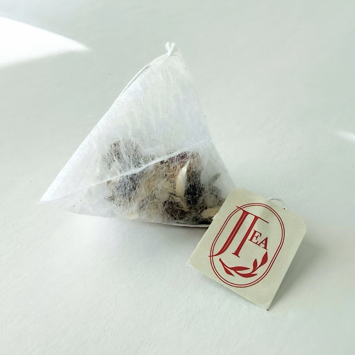 Triangular tea bag with a 'TEA' label on a white background