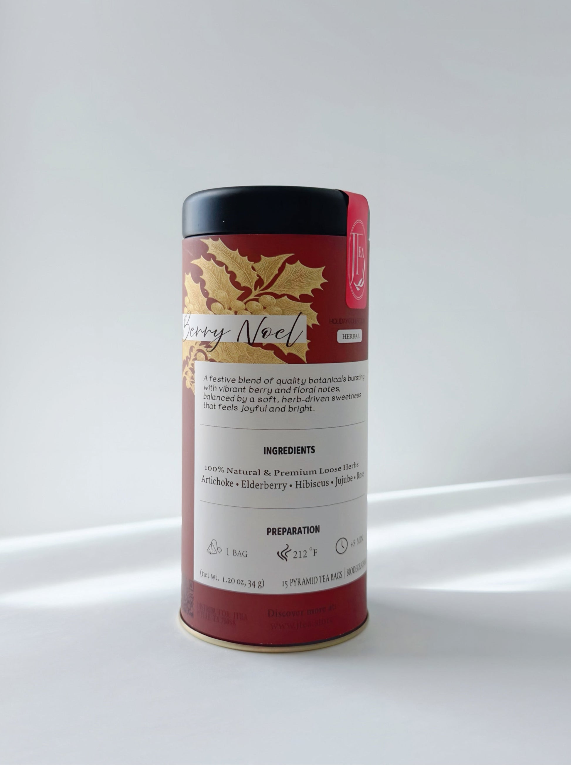 Red cylindrical tea canister with gold leaf design on a white background