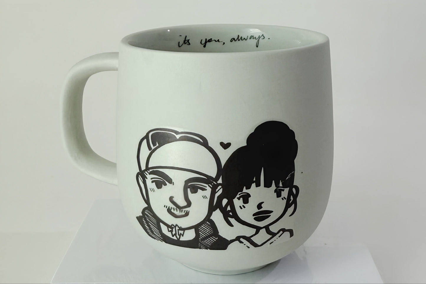 White mug with black illustrations of two people and text on a white background