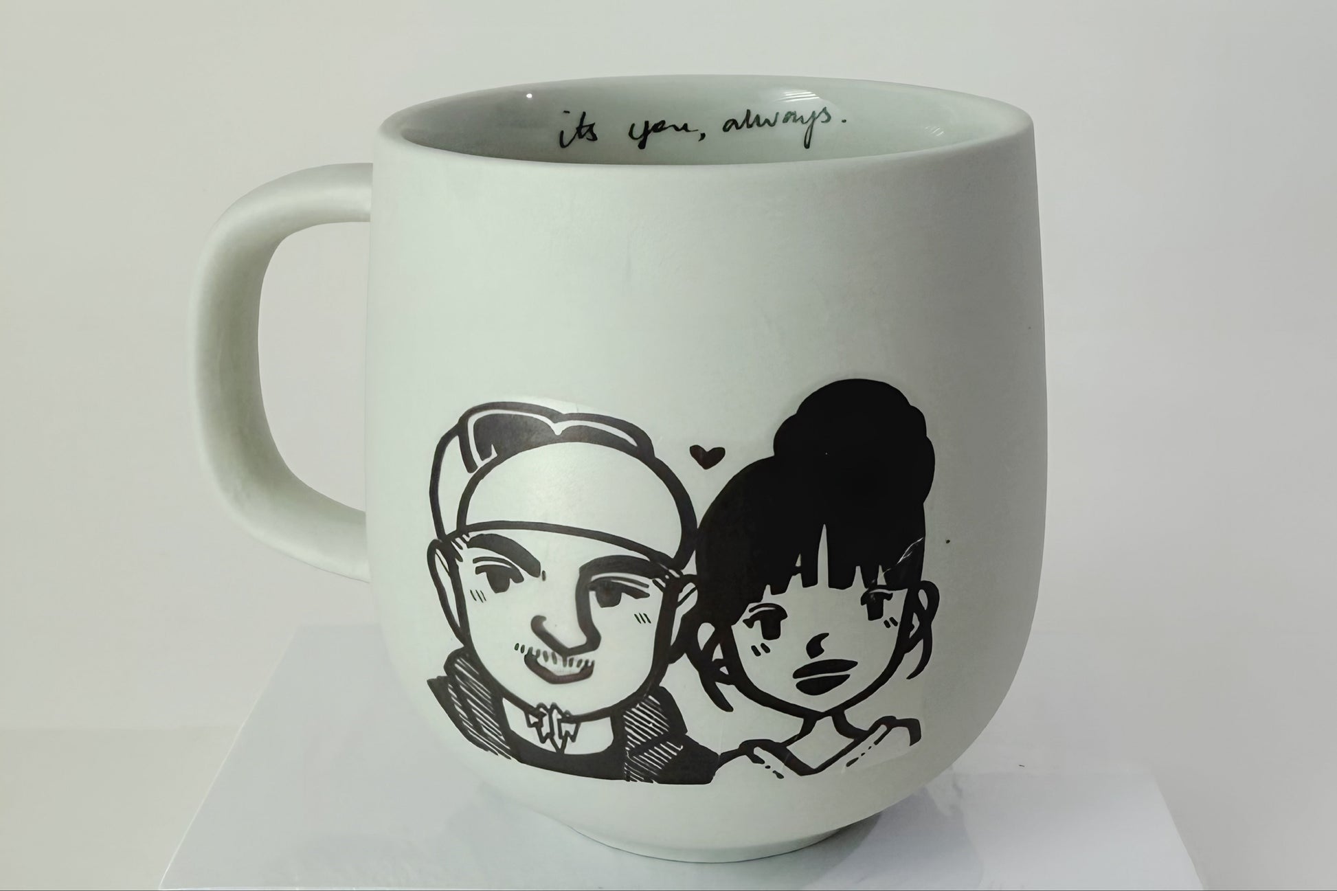 White mug with black illustrations of two people and text on a white background