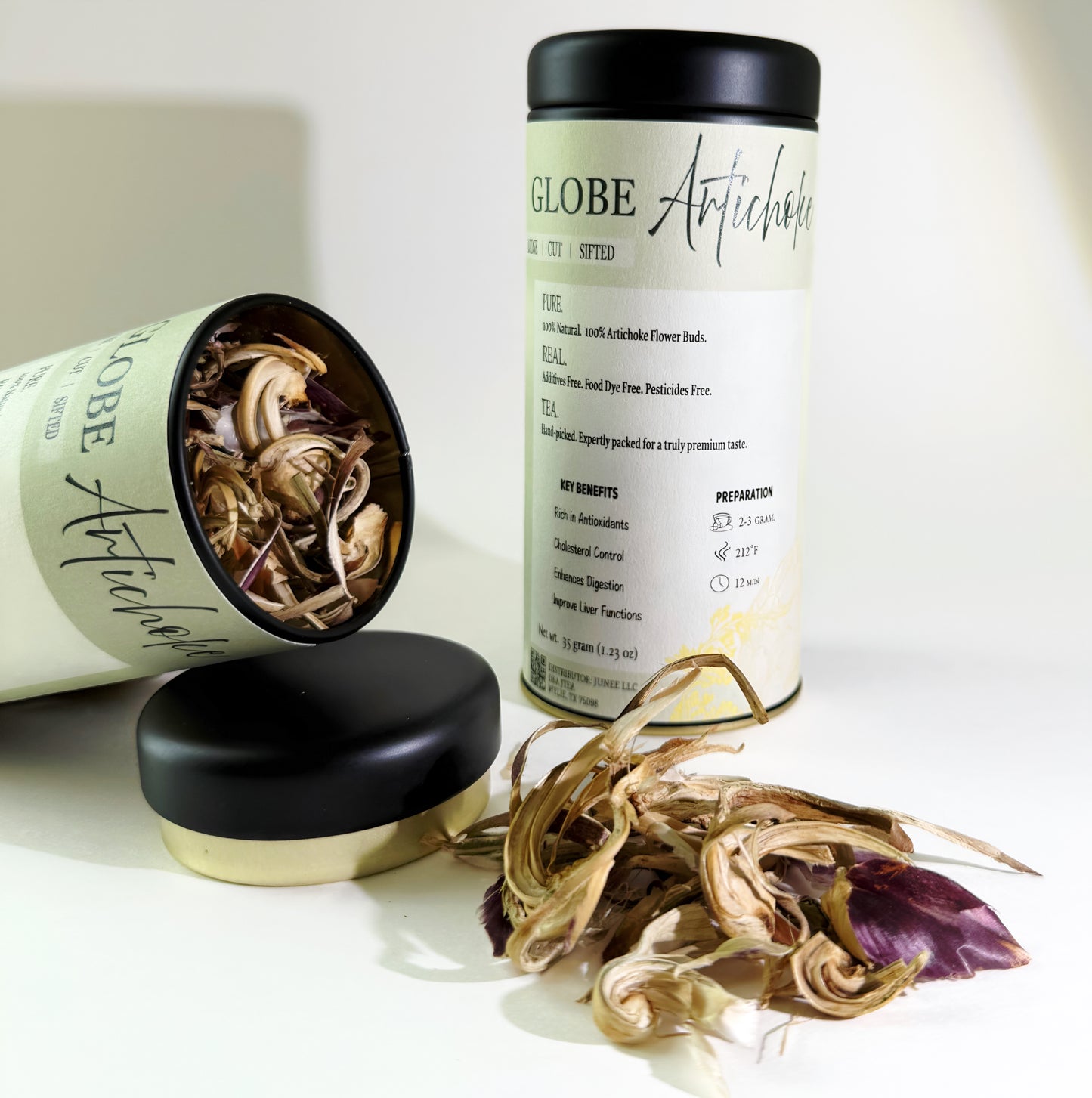 Two cans of 'Globe Artichoke' with their lids off, revealing dried artichoke flowers on a white background.