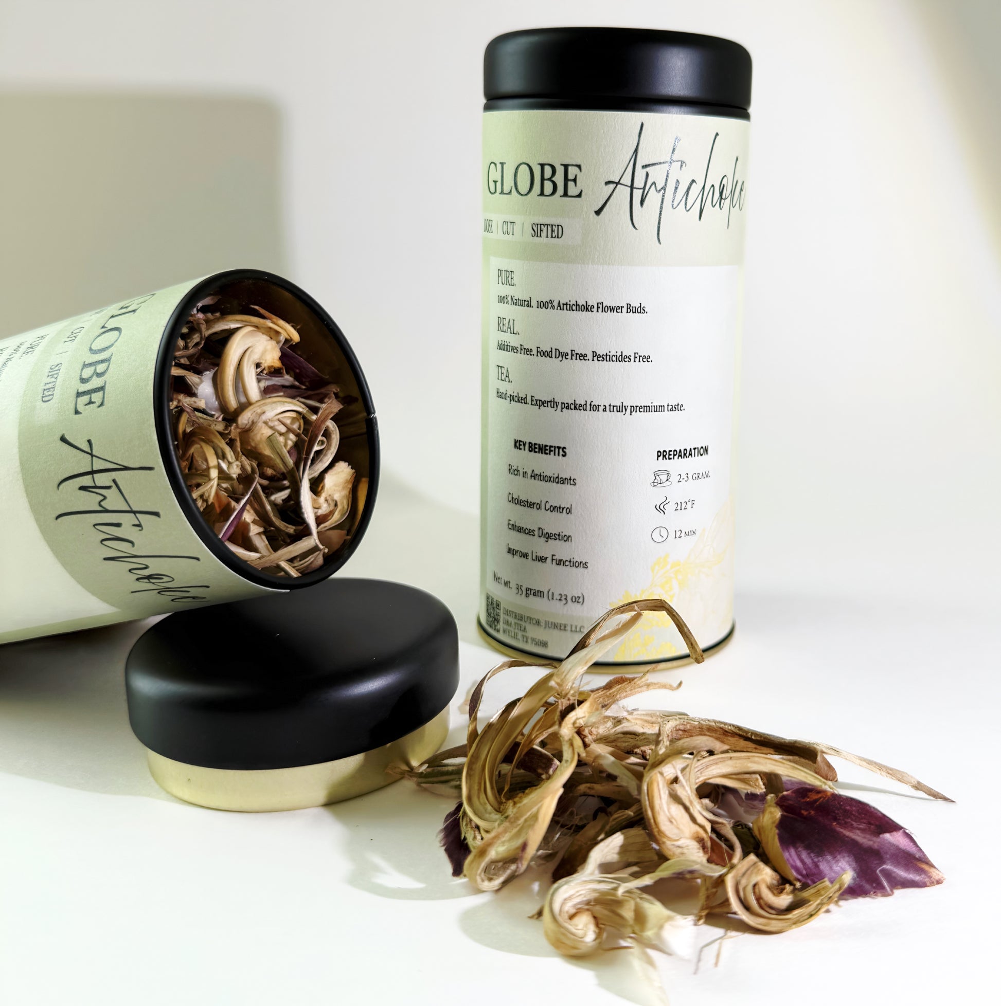 Two cans of 'Globe Artichoke' with their lids off, revealing dried artichoke flowers on a white background.