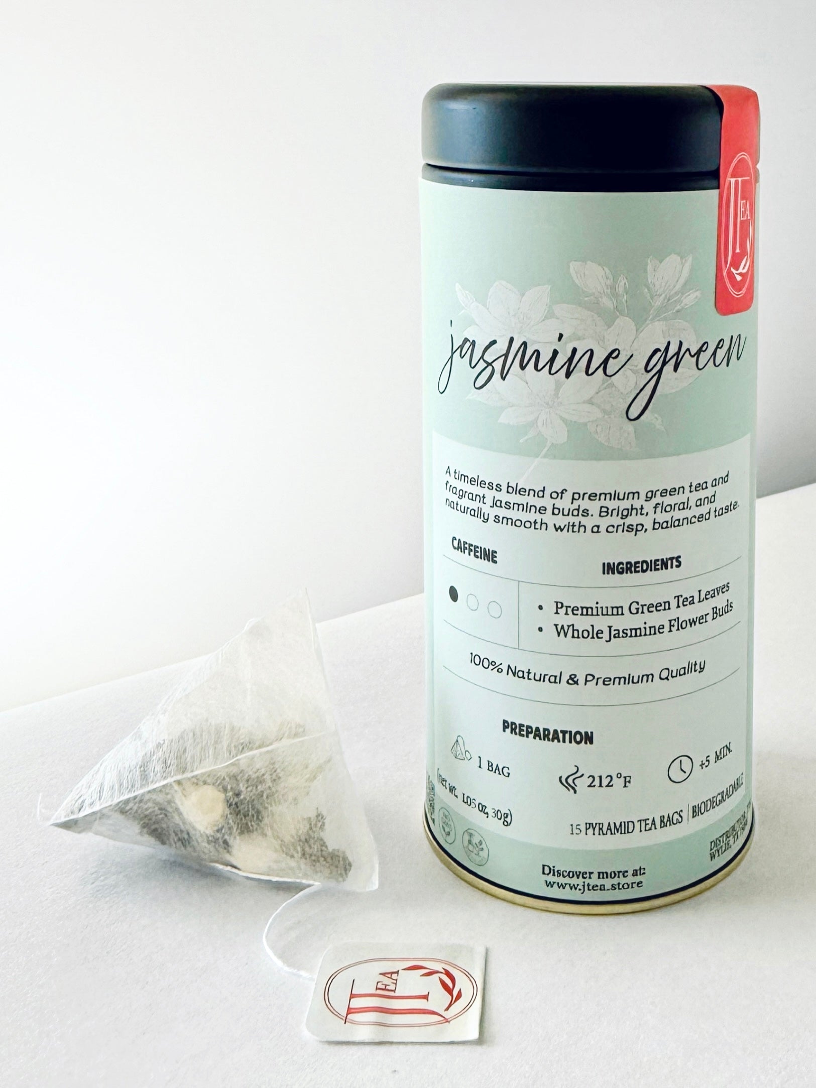 Tea canister labeled 'jasmine green' with tea bags on a white background